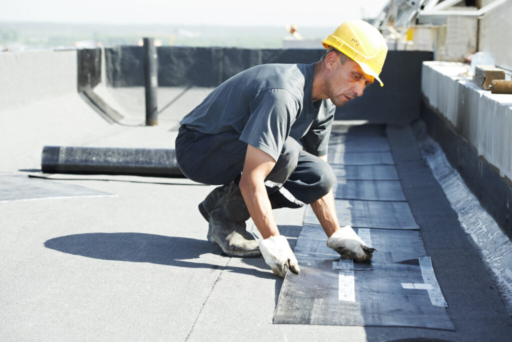 a man covering roof with roofing felt